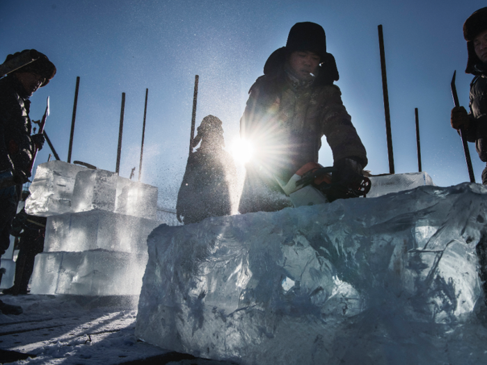 Workers use chainsaws to carve the ice into smooth building blocks for sculptures.