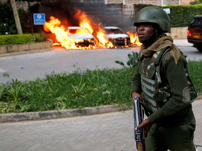 Cars near the complex caught on fire as gunshots rang out. Here, a policeman runs along the road to respond to ongoing attacks.