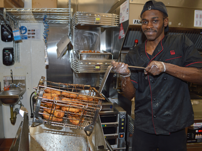 Once the chicken is cooked, the basket is lifted out of the pressure fryer and rests in the notches of this funneling contraption. The notches allow employees to quickly tip the basket over without dropping any of the chicken on the ground.