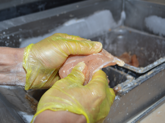 The employee manning the station hand-fillets each chicken breast by running their thumb up the seam. The team calls the smooth side of a chicken breast the crown, and the rough side — or the side with the seam — is the heel.