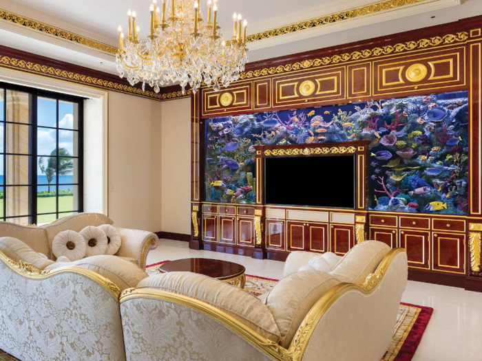 A family room is lined in mahogany and holds a saltwater aquarium with a 3D TV.