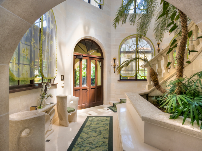 The house has a grand entrance with a foliage-covered foyer ...