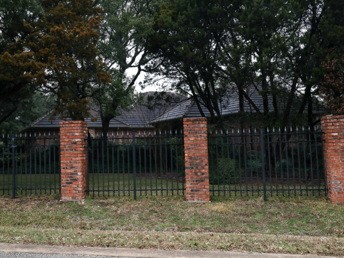 And the dark roof of this house can be seen past a fence and tree cover.