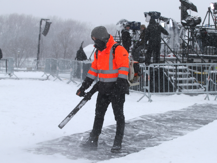 Workers cleared off walkways as snow continued to fall.