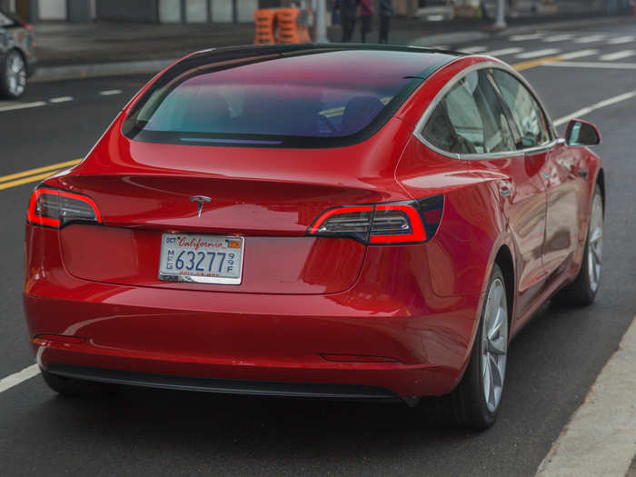 The roof is a continuous curve of glass, with a fastback rear hatch/trunk culminating in a crisp spoiler. The recessed door handles and the window trim are the only significant chrome on the Model 3.