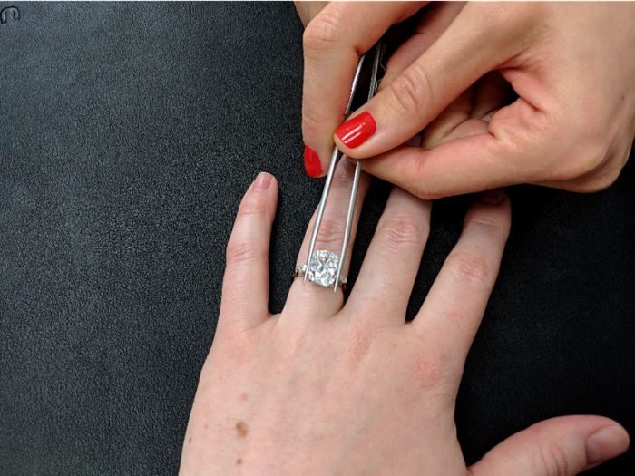 Wegman used a pair of tweezers to place the 5 carat diamond into an empty setting on my hand. Lanore told me they set loose stones in settings like this to give the idea of a completed ring look. Once a client decides on a look, they go back to hand-select accent stones to match the main diamond. The setting is then handmade.