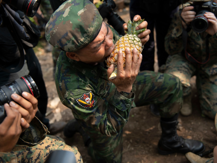 An instructor shows Marines how to bite into the skin of a pineapple.