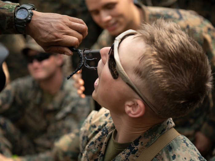 An instructor feeds a Marine a scorpion.