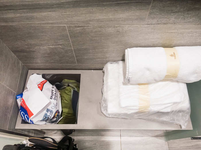 Each shower stall has a dressing area with a package of towels, including a bath sheet, a hand towel, and a bath mat. There