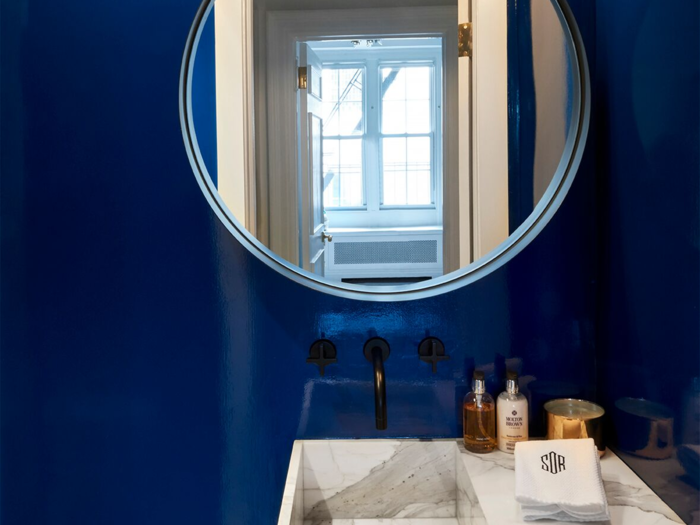 ... while a third features the same marble counters but with a circular mirror and deep blue wall paint instead.