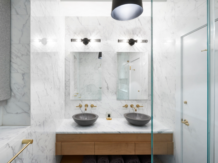 The marble trend continues into the bathroom, where marble extends from floor to ceiling. Two vessel sinks sit on the counter space, below two frameless, modern mirrors.