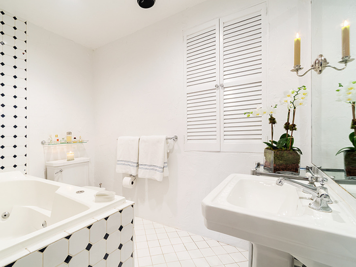 The bathroom, though spacious and clean, maintained its classic style with black and white tiles and candle lighting ...