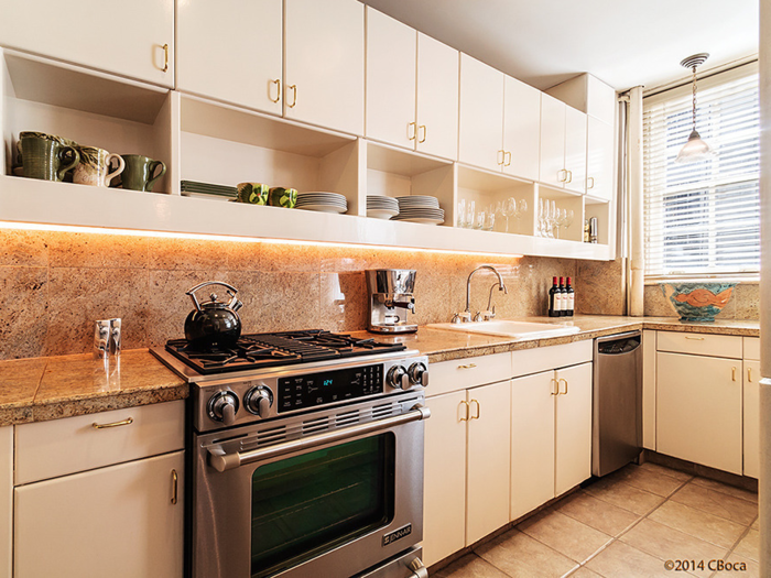 Previously, the kitchen had granite counters and beige cabinets with brass handles.