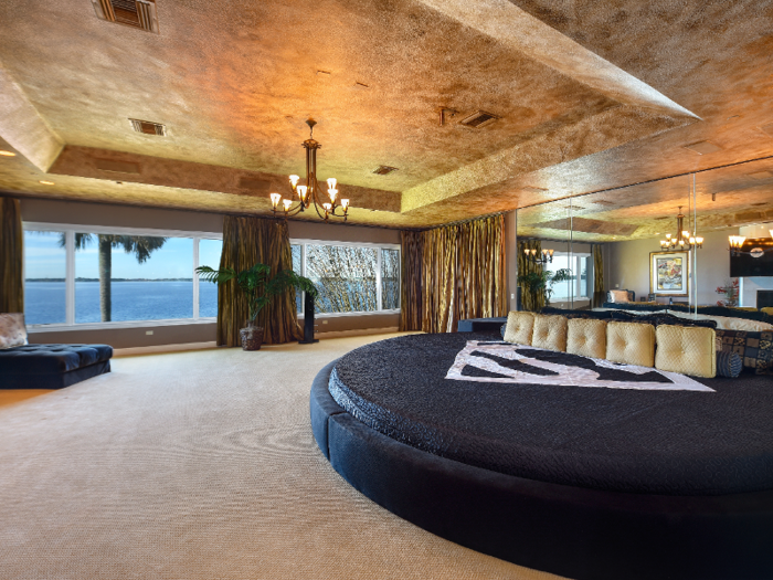 The master suite has a spacious walk-in closet, mirrored wall, gilded ceiling, and expansive views of the lake.