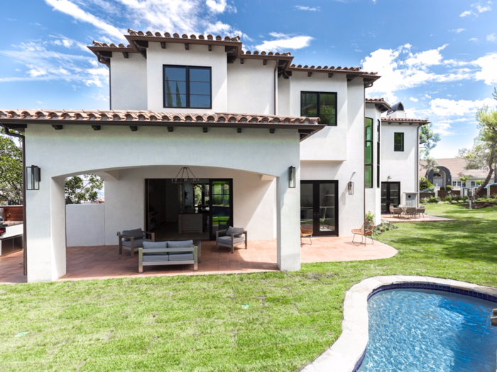 Outside, the grassy backyard has a built-in grilling station and swimming pool.