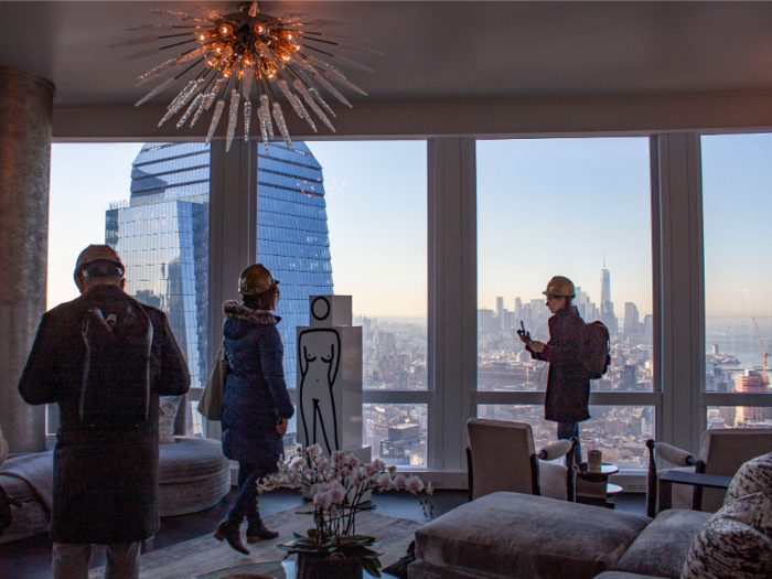 The living room has wraparound floor-to-ceiling windows for optimal city views.