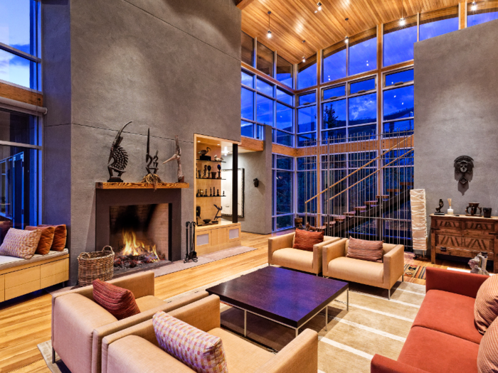 Inside the home, a spacious living room area offers plenty of seating. The massive room is complete with high ceilings, a fireplace, and a bay window bench seat.