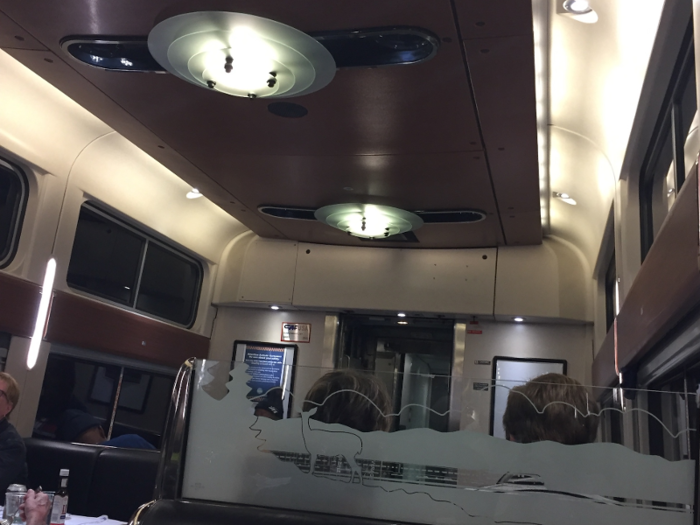  ... I made it to the dining car. The room was certainly a departure from the bare-bones snack car. This space had fancier light fixtures on the ceiling, wood panels on the walls, and white tablecloths on the table. 