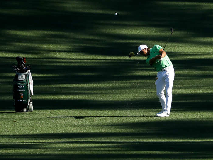 Rickie Fowler hits an approach shot in the shadows.