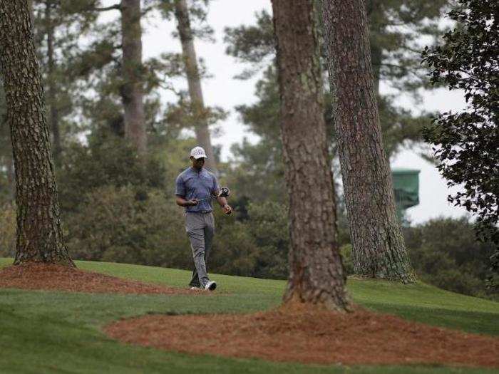 Tiger Woods walks alone among the trees.