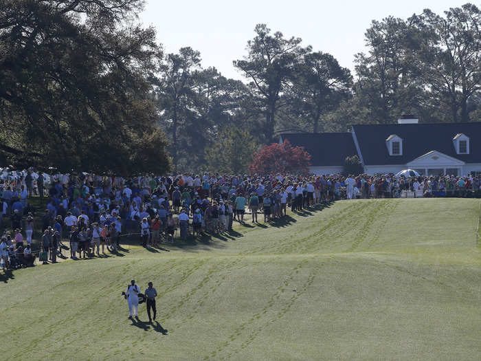 Jimmy Walker and his caddie walk among the tracks left in the dew-covered first hole.