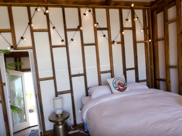 An interior shot reveals sleeping arrangements in a rustic room. Lounge set-ups include couch seating, a coffee table, and a mini-fridge.