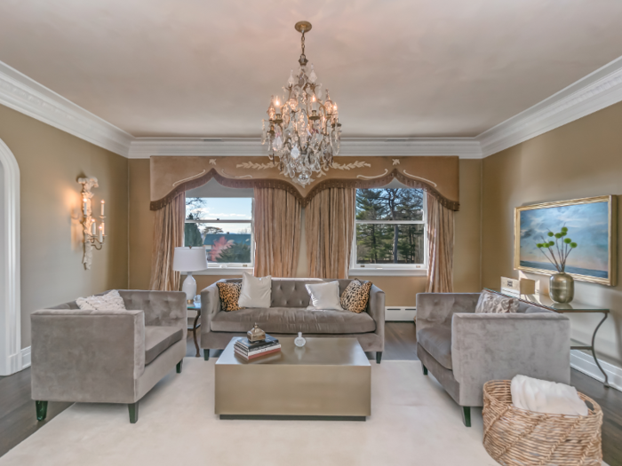 The home includes several living rooms, including a sitting area with gray velvet couches and a modern coffee table.