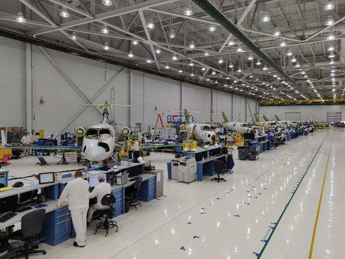 There are jets lined up along the walls of the production facility in various stages of completion.