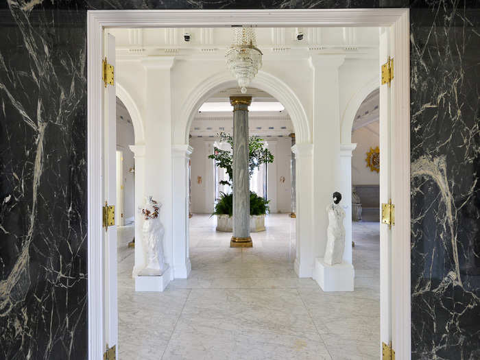 A circular entry with marble flooring features six Ionic columns, a domed ceiling, and four French doors leading to indoor gardens.