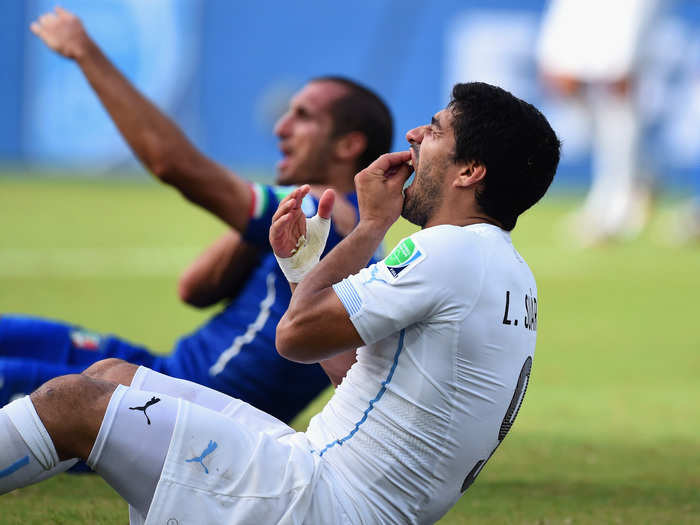 Luis Suarez bites, then clasps his teeth like he