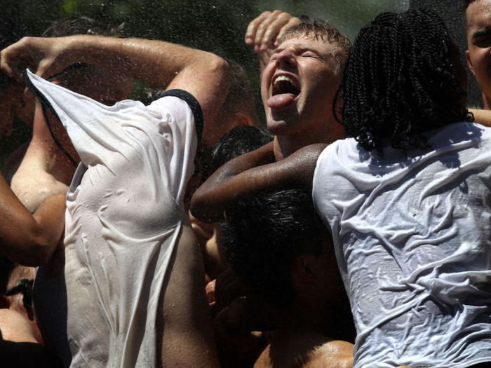 The students form around the base of the monument to provide as solid a foundation as they can, while their feet sink into the grass and mud beneath.