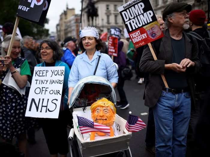 ... and a Trump figure being pushed in a stroller alongside a sign reading, "Keep his tiny hands off our NHS," which was a phrase seen widely around the march.