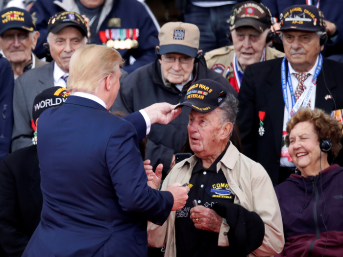 US President Donald Trump also took part in the commemoration, joining Macron at Omaha Beach after his trip to the UK and Ireland. Here he appears to place a cap saying "World War II Veteran" on a veteran