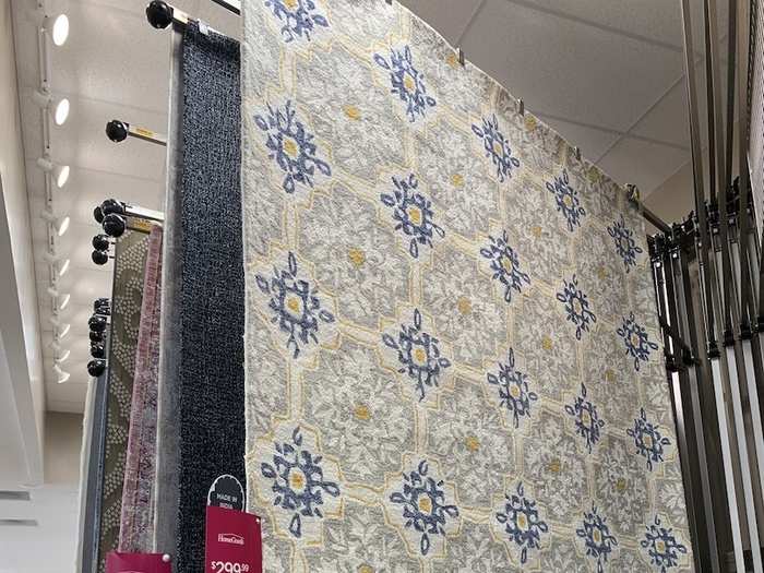 Area rugs in several sizes and patterns were hanging from a movable display. Customers are able to flip through them to find one they like, while being able to see the rug in its fully unrolled size. It