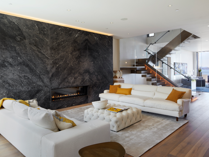 The home is sustainable, energy-efficient, and pre-certified LEED. The glass-enclosed staircase featured in the back of the photo was designed to spread natural light and air through each floor.