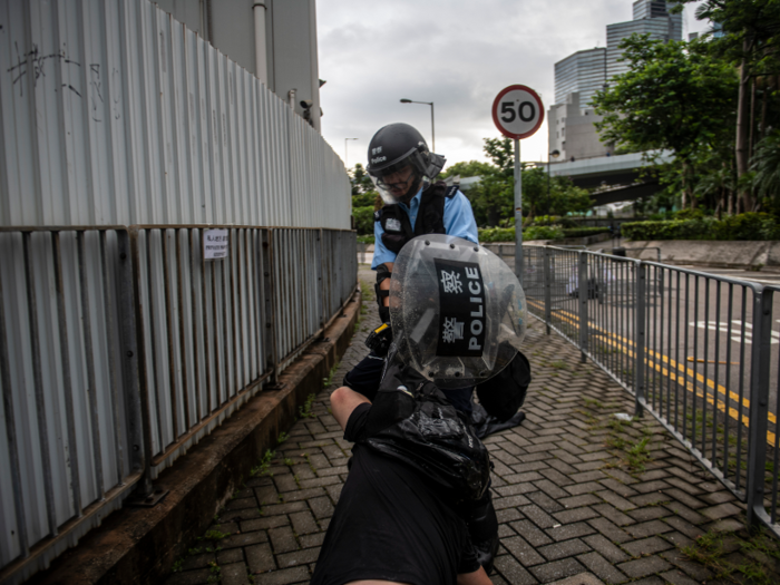 A protester can be seen being dragged on the ground by riot police.