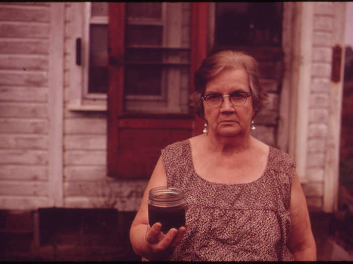 In 1973, Ohio resident Mary Workman filed a lawsuit against the Hanna Coal company, accusing it of polluting her drinking water. She holds a jar of dark-colored water from her well in this photo.