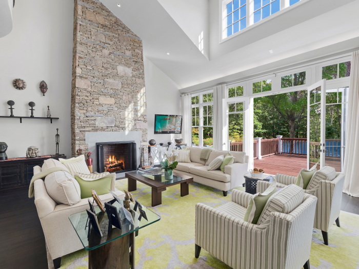 The seven-bedroom home features a spacious living room with a fireplace and high ceilings.