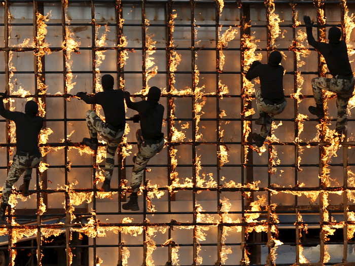 The Saudi security forces climb a flaming structure during a military parade.