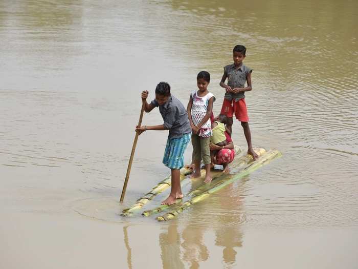 A man rows a raft in flood hit Jamunamukh village in Assam