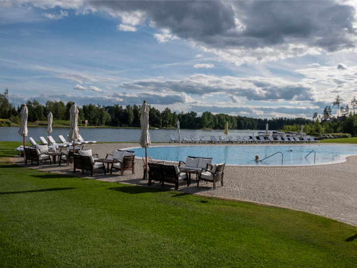 Outside is a resort-style pool with lounge chairs and umbrellas, which overlooks a picturesque lake.