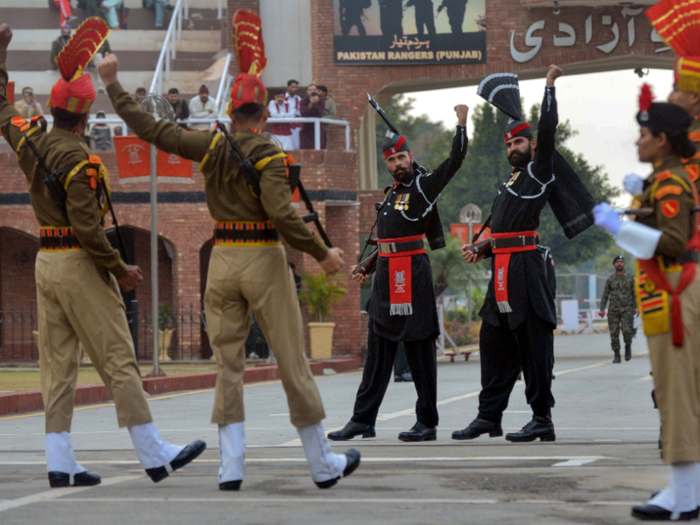 Pakistani and Indian border guards meet at the boundary between India and Pakistan. During an evening ceremony, the guards symbolically close the gate between India and Pakistan. The entrance to Pakistan can be seen in the background.