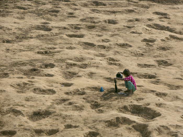 Refugees clean their clothes in water holes.