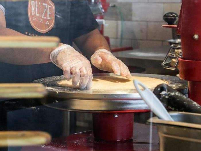 At Blaze, the journey begins with the dough, which is pressed into rounds at the front of the assembly line.