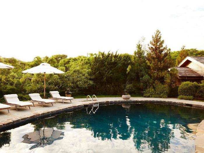 The outdoor swimming pool looks out at trees.