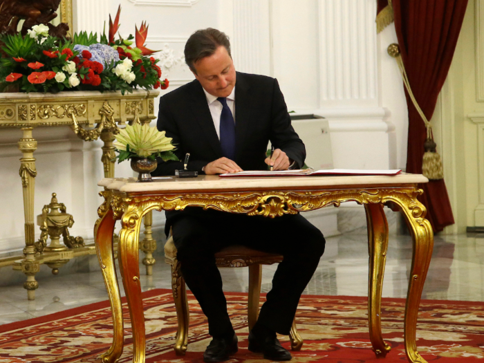 Former UK Prime Minister David Cameron is seen here in Jakarta signing a guest book with his left hand.