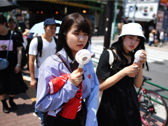 Other women in Tokyo use portable fans to try and cool off.