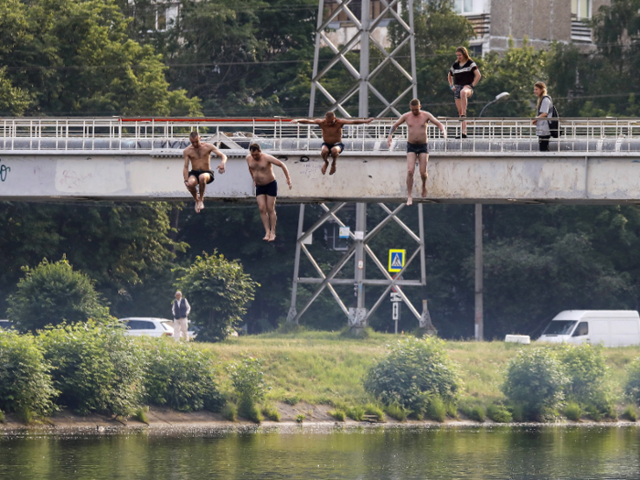 Men in the city take the plunge, leaping off a bridge into the cooling waters of a reservoir.