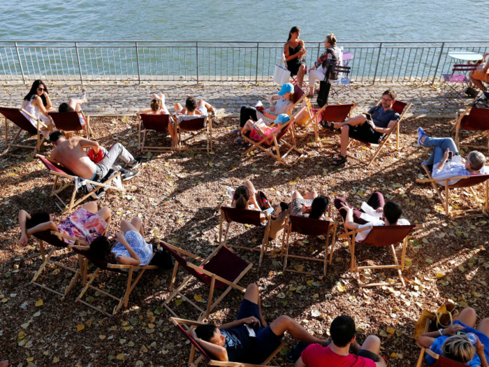 Across the English Channel, Parisians and tourists sit in the shade by the Seine River. One of the best ways to keep cool is to stay out of direct sun.