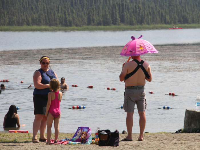 In Alaska, a man wields both an umbrella and an icy treat to keep himself and a child cool.